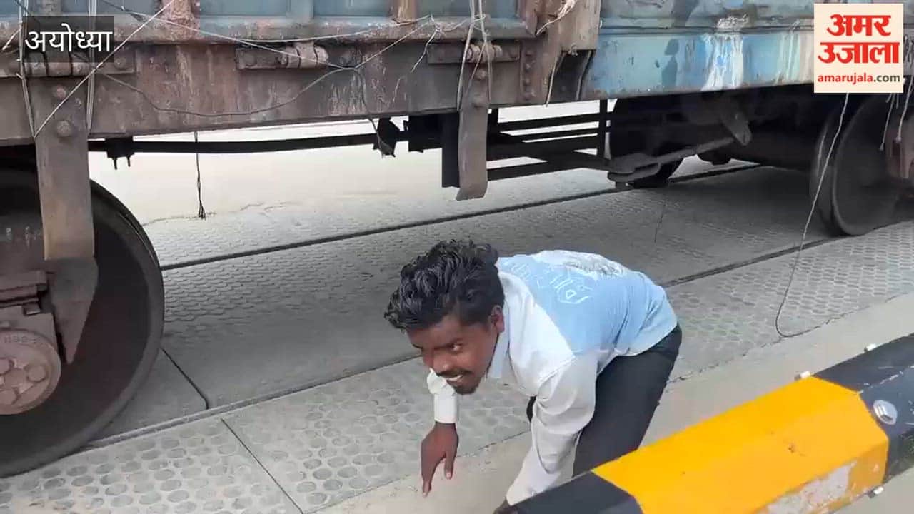 अयोध्या के बेनीगंज रेलवे क्रॉसिंग पर खड़ी मालगाड़ी के नीचे से जान जोखिम में डालकर गुजर रहे लोग