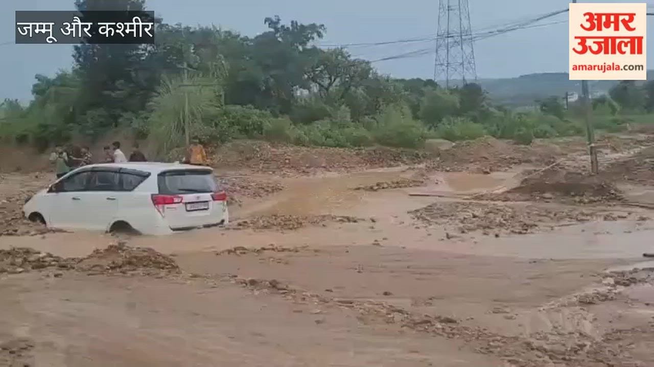 Innova gets stuck in a deep pit in a drain during heavy rain; pulled out by JCB.